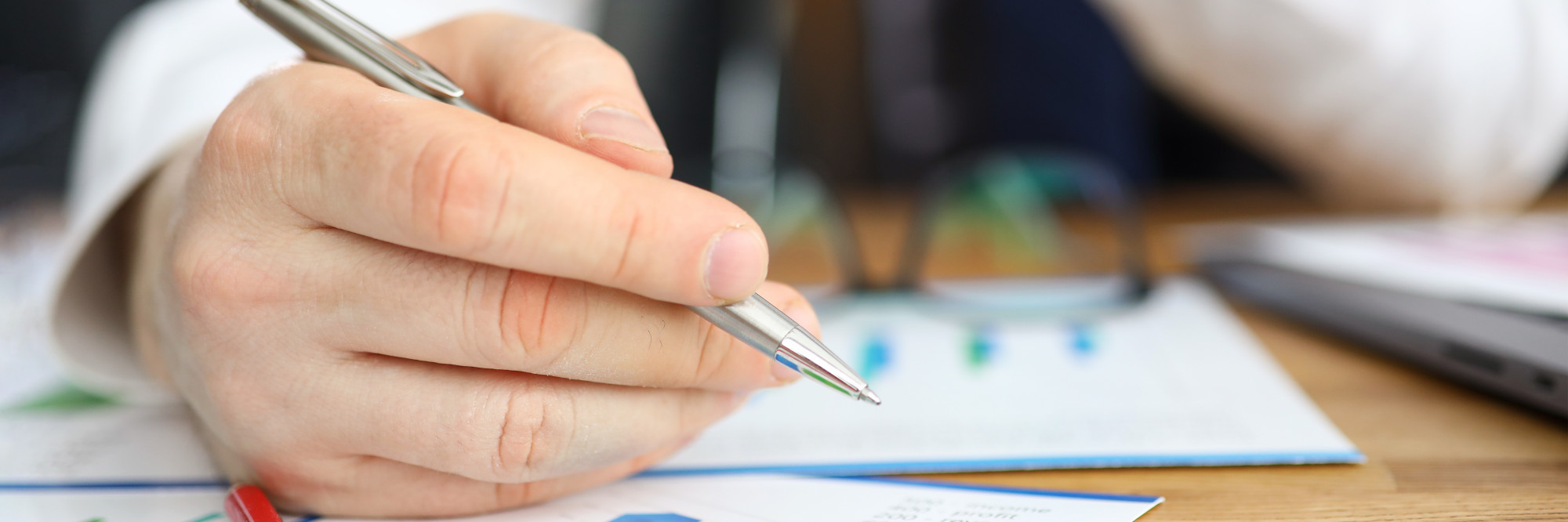 Hand hält Stift über Vertrag